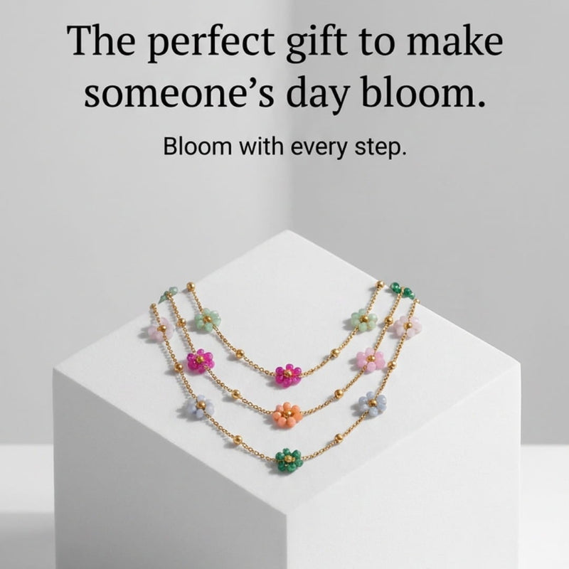 A set of delicate gold floral choker necklaces with colorful glass beads in pink, green, orange, and white, displayed on a white geometric pedestal against a light gray background with promotional text.
