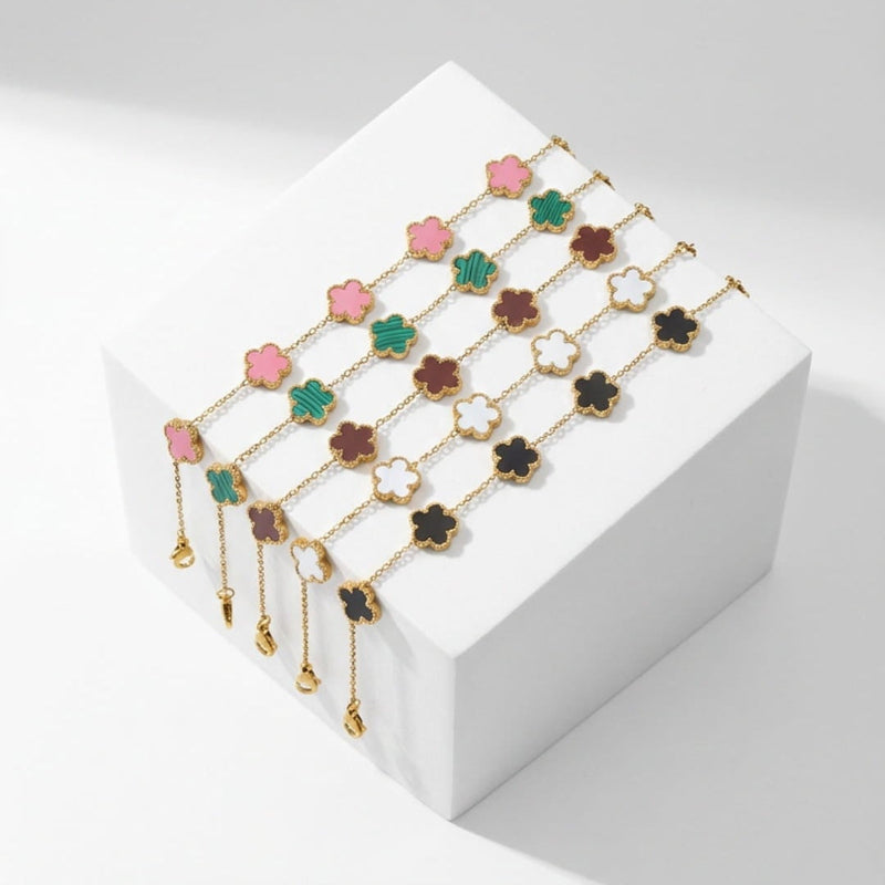 A set of gold floral statement bracelets displayed on a white geometric block against a light gray background, with promotional text above and below.