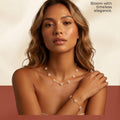 A woman modeling a delicate gold-plated pearl flower necklace and matching bracelet against a warm beige background with promotional text at the top.