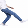 Person wearing blue jeans and white sneakers on a white background