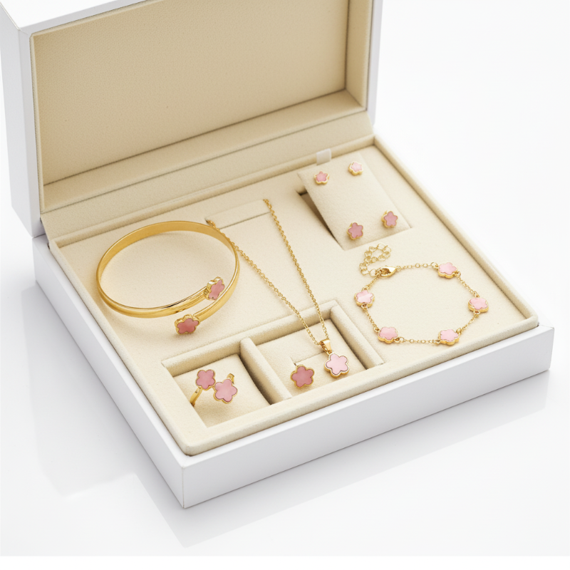 Gold jewelry set with pink flower-shaped stones, including a bracelet, necklace, earrings, and ring, displayed on a white background.